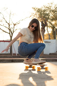 Backlit photography of an amazing young teenage girl rolling her longboard in a sporty way