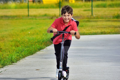 Full length portrait of happy boy riding bicycle on road