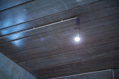 Low angle view of light bulb hanging on ceiling