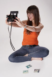 Beautiful woman taking selfie through camera against white background