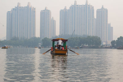 Passenger craft sailing in river against buildings