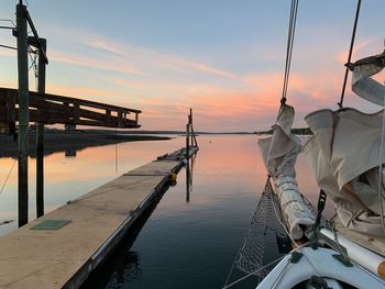 Sailboats moored on sea against sky during sunset