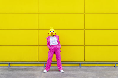 Full length of girl standing against yellow wall