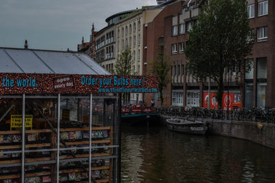 Sailboats moored on canal by buildings in city against sky