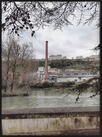 Factory by lake against sky