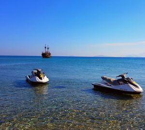 Boat sailing on sea against clear blue sky