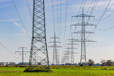 Low angle view of electricity pylons against sky