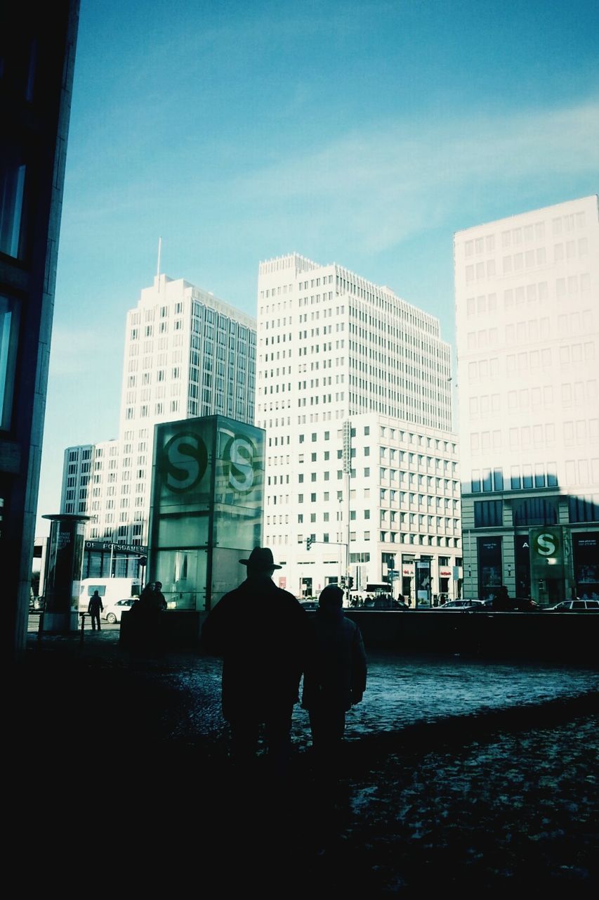 building exterior, architecture, built structure, city, lifestyles, men, city life, silhouette, leisure activity, sky, rear view, building, person, sunlight, skyscraper, day, street, full length