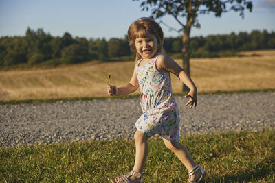 Charming child in a sundress running down the street in the suburbs