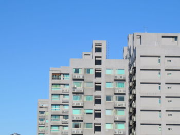 Low angle view of modern buildings against clear blue sky