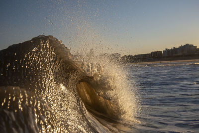 Waves splashing in sea against clear sky