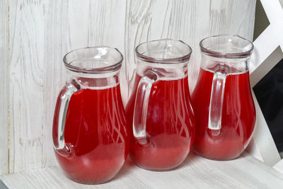 Three decanters with red berry juice on the sideboard. horizontal photo