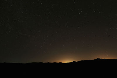 Low angle view of silhouette mountain against sky at night