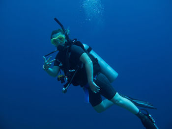 Woman gesturing while scuba diving in sea