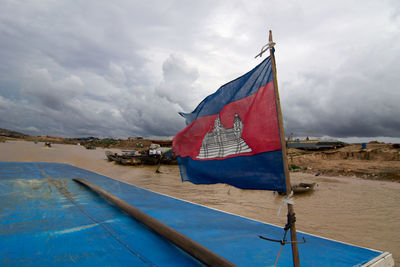 Scenic view of flag on sea against sky