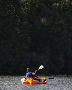 Man sitting in boat against trees