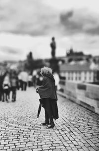 Woman standing on footpath in city