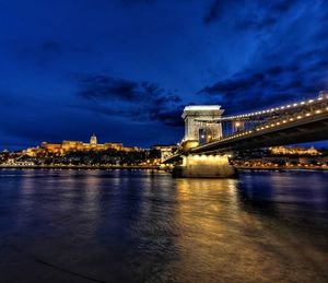 Illuminated bridge over river against sky at night