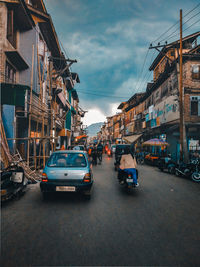 Cars on road by buildings against sky