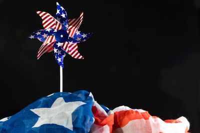 Close-up of pinwheel toy on flag against black background