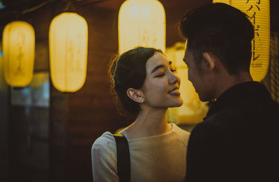 Close-up of couple embracing while standing outdoors at night