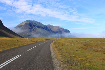 Road by mountains against sky