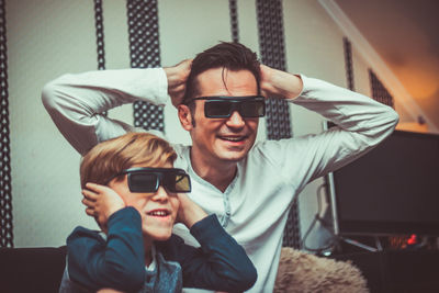 Father and son watching tv on sofa at home