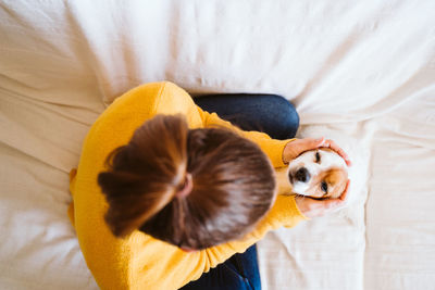 Directly above shot of woman sitting with puppy on bed