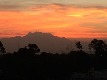 Scenic view of silhouette mountains against orange sky