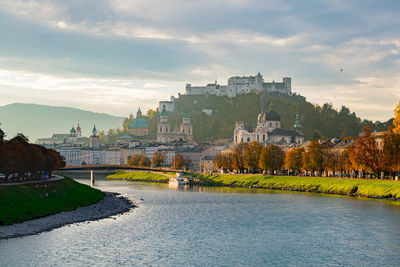 Buildings by river against sky