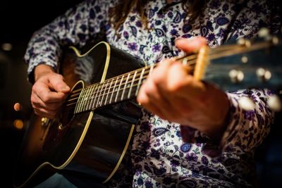 Midsection of man playing guitar