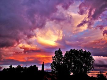 Low angle view of silhouette trees against dramatic sky