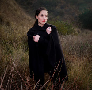 Portrait of young woman standing on grassy field