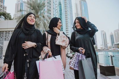 Cheerful women wearing shopping bags standing outdoors