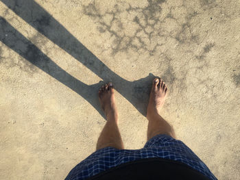 Low section of person standing on sand