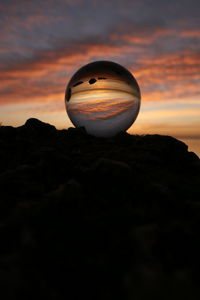 Silhouette rock on land against sky during sunset