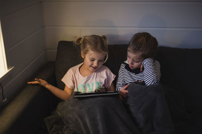 Sisters using digital tablet on sofa