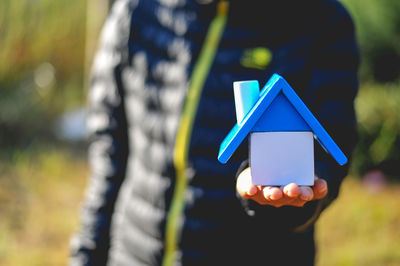 Midsection of man holding toy blocks forming model home