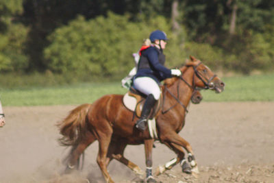 Young man riding horse on field