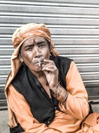 Portrait of woman smoking bidi against shutter