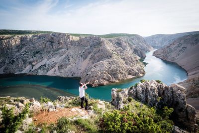 Woman standing on rock by mountain against sky