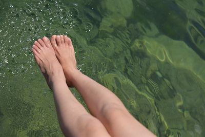 Low section of woman over lake during sunny day