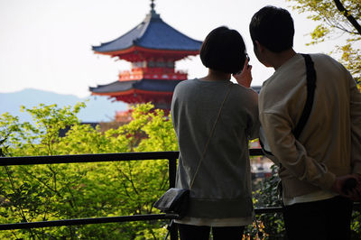 Rear view of people standing outside temple against building