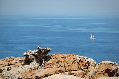 Sailboat sailing on rock by sea against sky