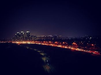 Illuminated cityscape against clear sky at night