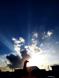 Low angle view of silhouette hand against building during sunset