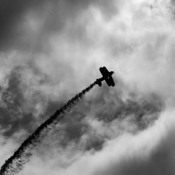 Low angle view of silhouette airplane flying against sky