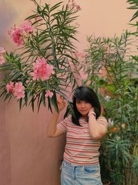 Portrait of young woman standing against the wall with flowers 
