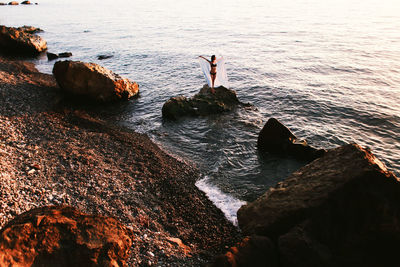 High angle view of woman posing on rock in sea