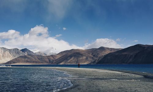 Scenic view of sea by mountains against sky